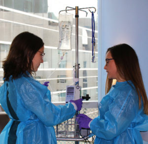As part of the oncology residency program, Meaghan Ekstrom, RN (right), trains new graduate RN, Anna Campbell, on how to set up a chemotherapy infusion in an IV pump.