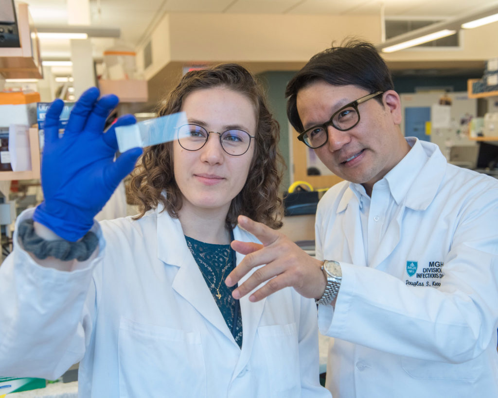 Ragon Institute research technician Alice Linder and Doug Kwon, MD, PhD, examine a microscope slide that holds tissue from an HIV infected donor.