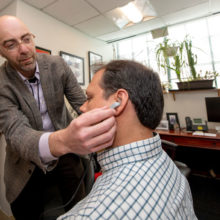 Vitaly Napadow, PhD (left), uses a prototype to demonstrate placement of his nerve stimulation device.