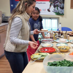 After-school cooking instructor Eliza Abdu-Glass helps student Alexandra Mercado choose ingredients for a sandwich.
